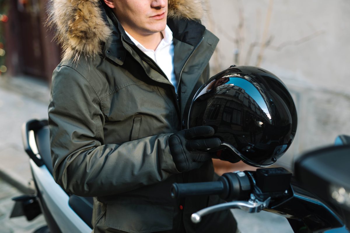 un homme avec un casque de scooter à la main