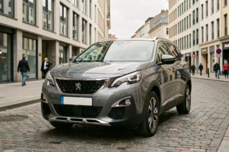 Peugeot 5008 gris métallisé garé en ville, vue 3/4 avant sur pavés parisiens pour guide d'achat moteur essence diesel hybride